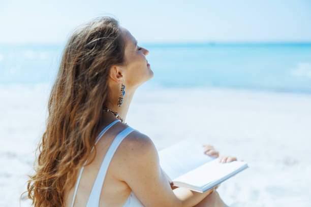 istock relaxed elegant woman on seacoast with straw bag and book 2148025840