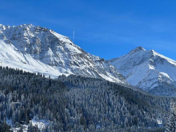 Beautiful sunlit and snow-capped alpine peaks above the Swiss tourist sports-recreational winter resorts of Valbella and Lenzerheide in the Swiss Alps - Canton of Grisons, Switzerland (Schweiz) stock photo