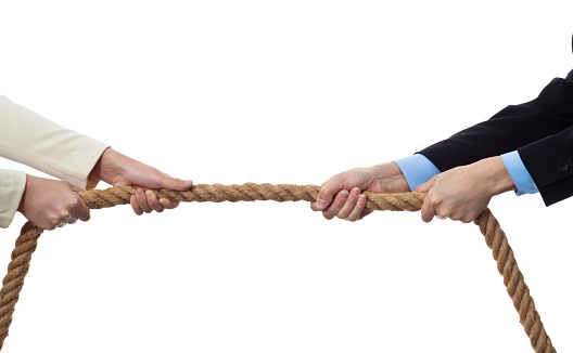 Two business person playing tug-of-war.