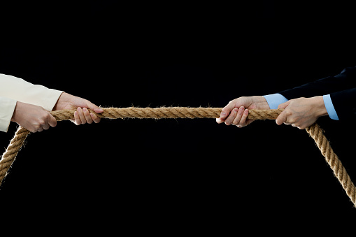 Two business person playing tug-of-war.