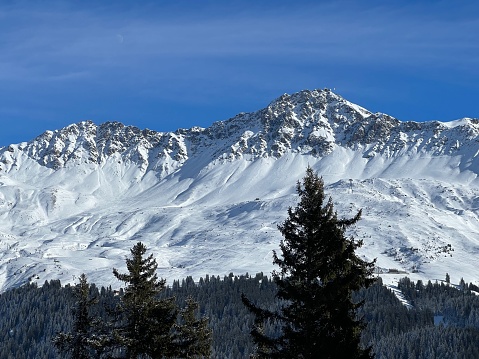 Beautiful sunlit and snow-capped alpine peaks above the Swiss tourist sports-recreational winter resorts of Valbella and Lenzerheide in the Swiss Alps - Canton of Grisons, Switzerland (Schweiz)