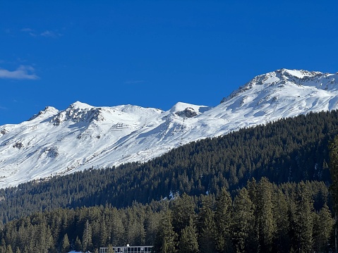 Beautiful sunlit and snow-capped alpine peaks above the Swiss tourist sports-recreational winter resorts of Valbella and Lenzerheide in the Swiss Alps - Canton of Grisons, Switzerland (Schweiz)