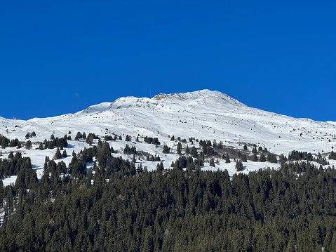 Beautiful sunlit and snow-capped alpine peaks above the Swiss tourist sports-recreational winter resorts of Valbella and Lenzerheide in the Swiss Alps - Canton of Grisons, Switzerland (Schweiz)