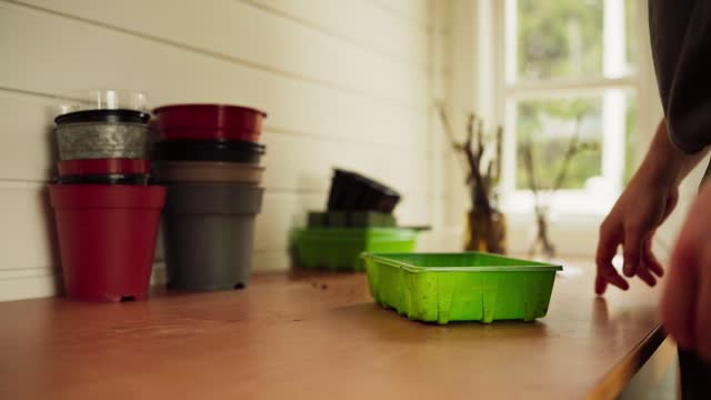 Gardener Prepares Rectangular Plastic Pot For Planting In Greenhouse. closeup shot