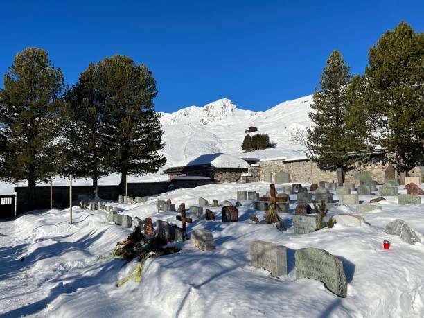 A miniature cemetery covered with fresh snow next to Arosa's mountain chapel (Das Bergkirchli Arosa) in the Swiss alpine winter resort Arosa - Canton of Grisons, Switzerland stock photo