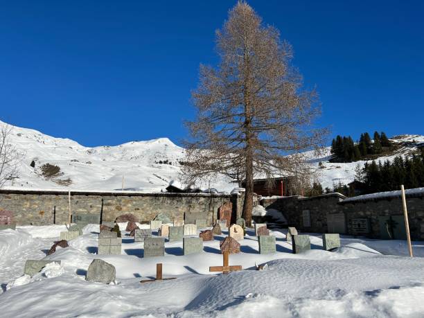 A miniature cemetery covered with fresh snow next to Arosa's mountain chapel (Das Bergkirchli Arosa) in the Swiss alpine winter resort Arosa - Canton of Grisons, Switzerland stock photo