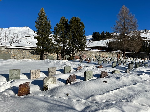 A miniature cemetery covered with fresh snow next to Arosa's mountain chapel (Das Bergkirchli Arosa) in the Swiss alpine winter resort Arosa - Canton of Grisons, Switzerland