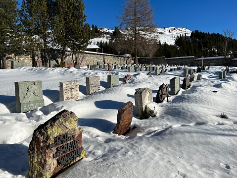 A miniature cemetery covered with fresh snow next to Arosa's mountain chapel (Das Bergkirchli Arosa) in the Swiss alpine winter resort Arosa - Canton of Grisons, Switzerland