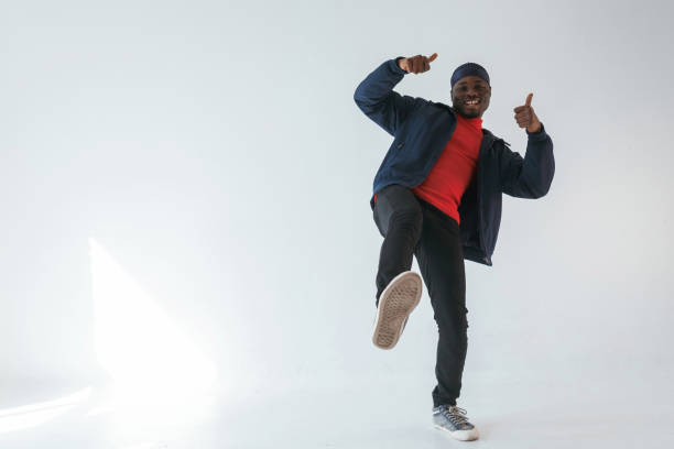 istock Showing thumbs up, having fun. Black man in cap is in the studio against white background 2148030002