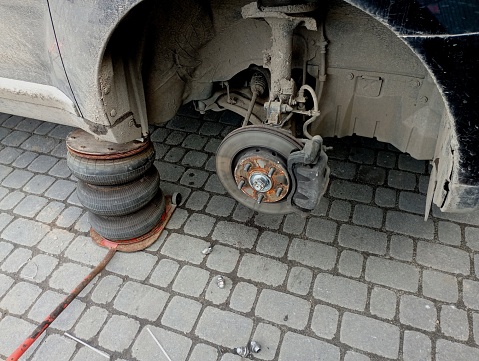 Raised on a jack by a pneumatic machine for changing wheels. Seasonal replacement of tires for maintenance of the braking system and running vehicle. The topic of car repair and car service.