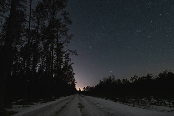 istock Night scene and starry sky. Road through the forest in winter. 2148031624