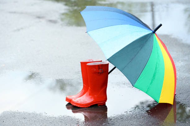 istock Red rubber boots with umbrella in puddle after rain 2148031903