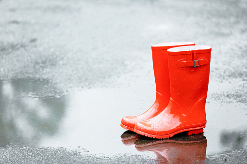 Red rubber boots in puddle after rain