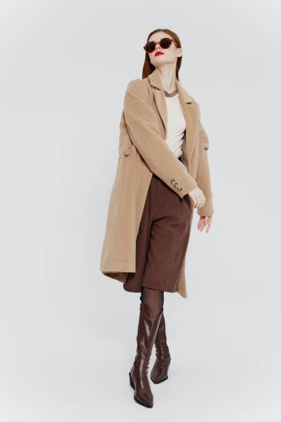 istock Stylish redhead lady in beige coat glasses posing on a white background in the studio 2148033467