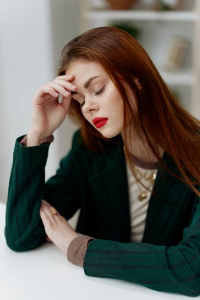 istock A sad, brooding, tired young red-haired woman at the table is thinking about a difficult decision in life. Life problems, crises, burnout concept 2148033817