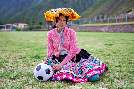 Portrait of woman with a traditional dress from Peru of the Quechua ethnic group soccer players on the soccer field with a ball