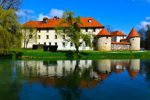 View of Otočec castle and a reflection of the castle in the water of Krka rive in Dolenjska, Slovenia