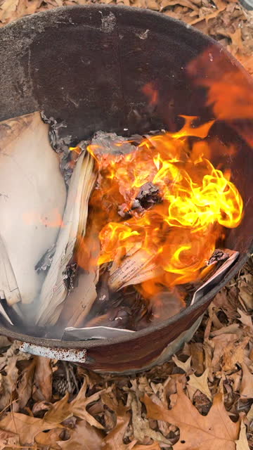 Documents burn and flame up inside metal trash can