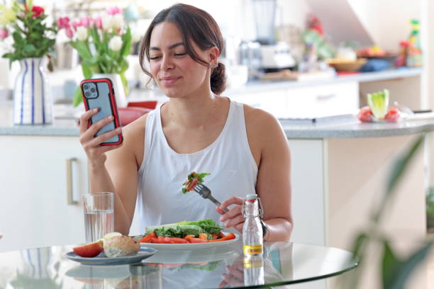 istock Multiracial woman uses phone while eating salad 2148036579