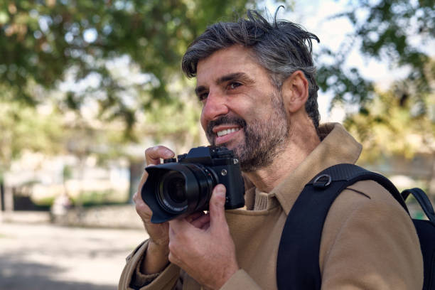istock Mature gray haired man with photo camera in park 2148037342