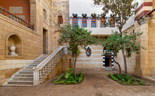 Courtyard of Prince Naguib Palace, Cairo, Egypt where lush greenery and elegant architecture create a peaceful sanctuary. The inviting staircase beckons exploration