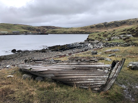 An old, broken wooden boat in the rugged landscape of the Isle of Lewis in April, near Dun Carloway, Outer Hebrides, Scotland, United Kingdom