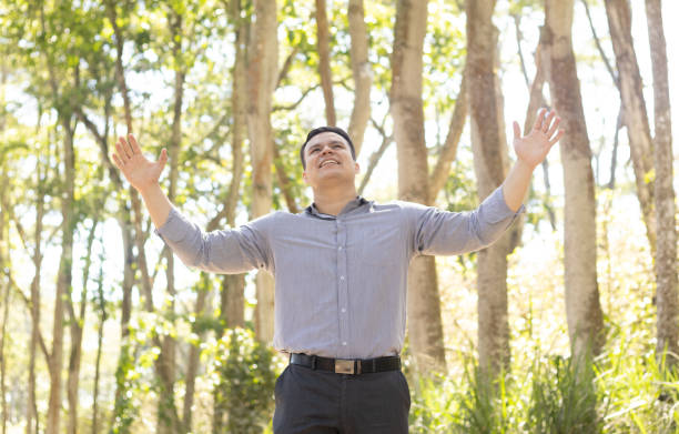 istock young latin man facing front with arms open praying 2148042001