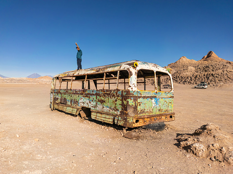 man standing on abandoned truck in vallecito valley in the Atacama desert