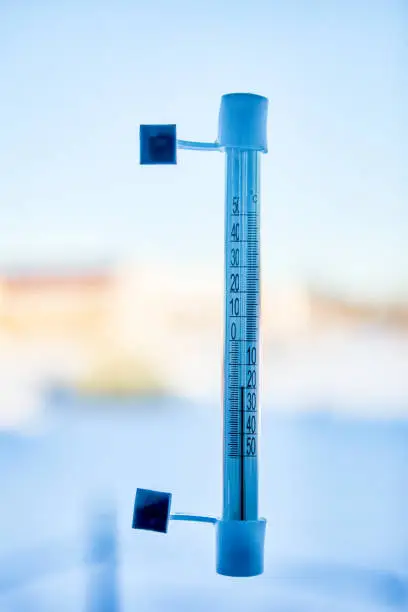 Photo of An outdoor thermometer is mounted on window glass using adhesive tape, scale shows 20 degrees Celsius below zero.