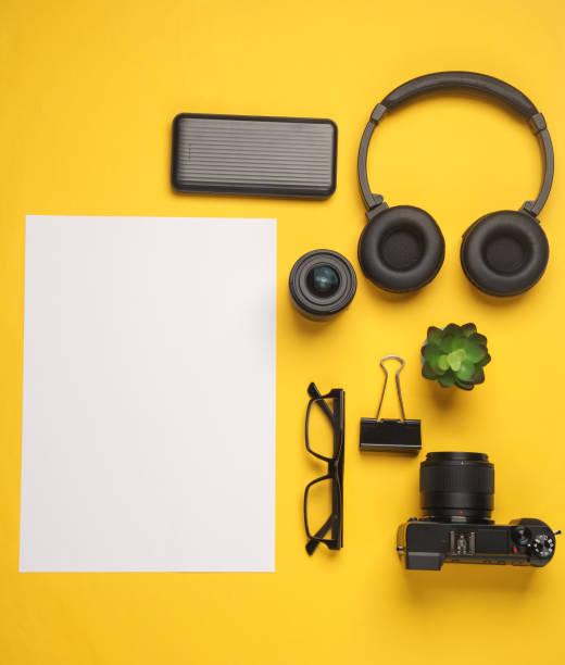 istock Camera and accessories with white blank sheet of paper for text on yellow background 2148043125