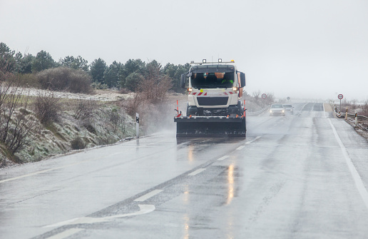 Snow plow patrolling the road in a sleet. North Spain road