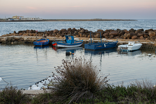 Calm morning in a small village on the west of the mediterranean island. Small port created from rocks. Colorful boats. Spiaggia Sibiliana, Marsala, Sicily, Italy.