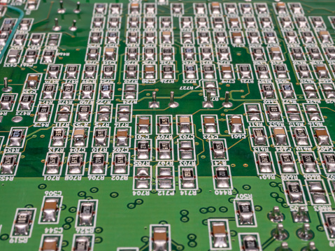 Green circuit board with many components on it. Selective focus.
