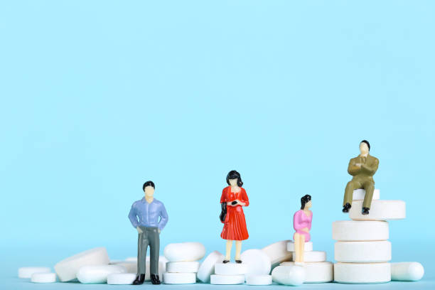 istock Miniature people with white pills on blue background 2148047809