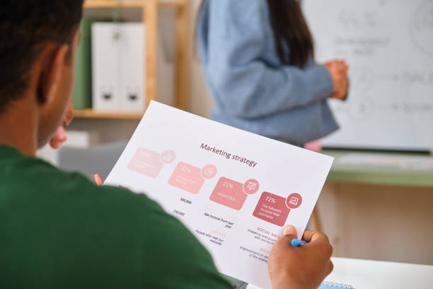 istock A man is reading a marketing strategy paper while attending to a presentation. 2148049036