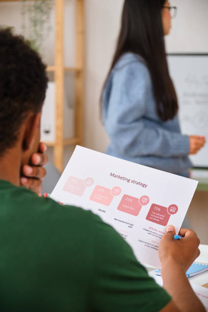 istock A man is reading a marketing strategy paper while attending to a presentation. 2148049068