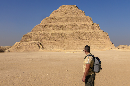 Real man in profile looking at the step pyramid of Zoser in a sunny day with blue sky without people