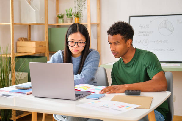 istock A man and a woman are sitting at a table with a laptop open working. 2148049247