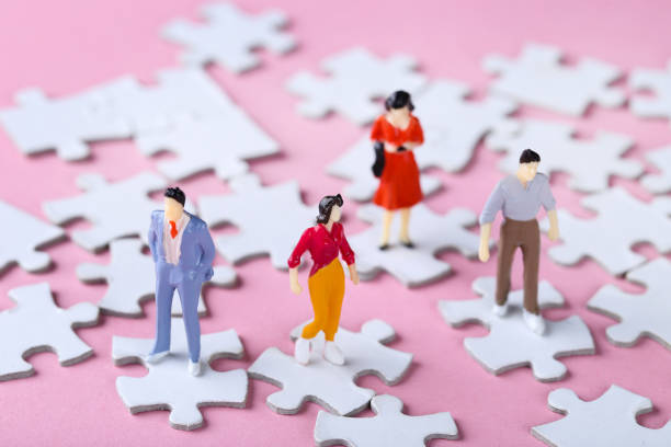 istock Miniature people with white jigsaw puzzles on pink background 2148049289