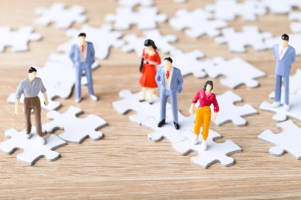 istock Miniature people with white jigsaw puzzles on wooden table 2148049388