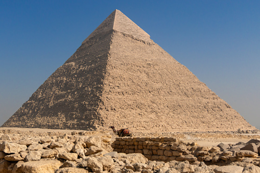 Camel caravan in front of the Great Pyramid of Menkaure in the Giza Pyramid Complex on background Cairo city skyline. Tourists continued to swarm the historic sites at Giza.