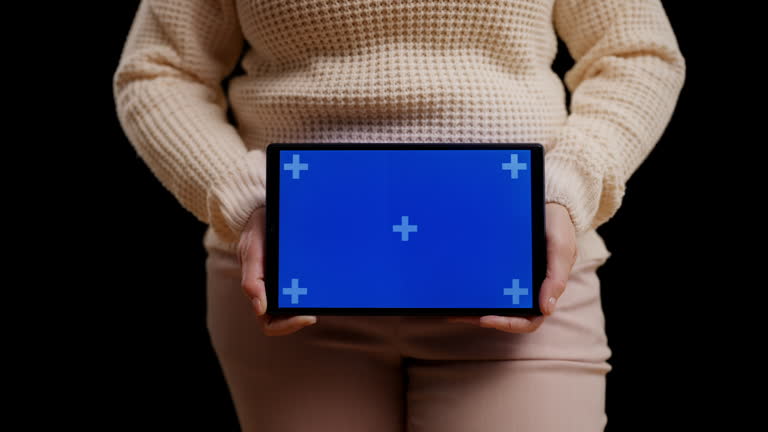 Close-up of woman in casual wear holding tablet with blue screen for your text
