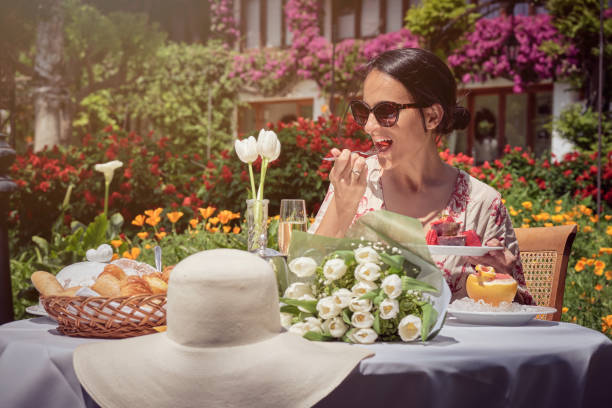Stock photo of happy woman enjoying breakfast in the garden during sunny day.