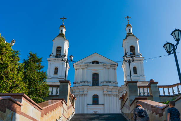 Vitebsk, Belarus, September 9, 2023. A beautiful white stone cathedral in the Italian style with columns and bell towers on the sides, restored on the site of the destroyed one, tiered bell towers with crosses, icons on the walls, a wide staircase, walking people, culture and religion, European traditions, a city landmark, autumn.