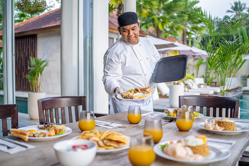 Portrait of personal chef serving dish in luxury villa
