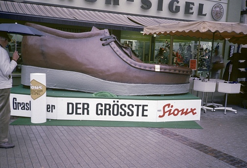 Germany (exact location not known), 1982. Shoe advertising campaign in front of a shoe shop in a pedestrian zone in western Germany. Also: passers-by.
