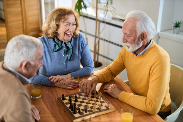 istock Group of happy mature friends talking while playing chess  at home. 2148055185