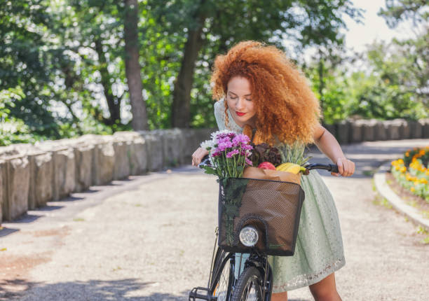 Shot of pretty young woman with a bike enjoying a springtime while going to market for grocery shopping