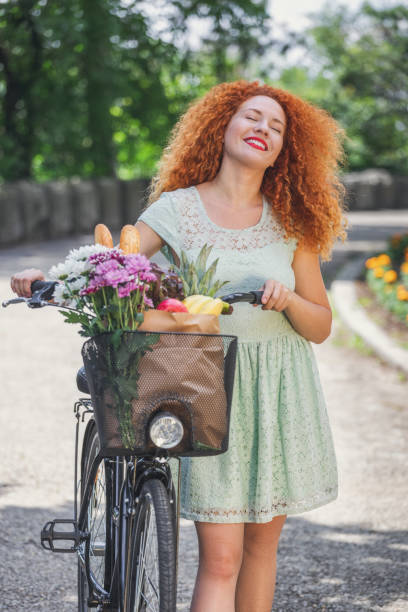 Shot of pretty young woman with a bike enjoying a springtime while going to market for grocery shopping