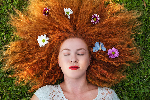 A beautiful young woman lying down on green grass. Spring beauty concept
